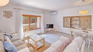 Een woonkamer met een bank, salontafel, televisie en een eethoek met stoelen en een tafel.