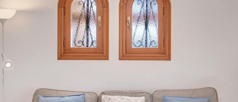 A room with a sofa, two arched windows, and a lamp.