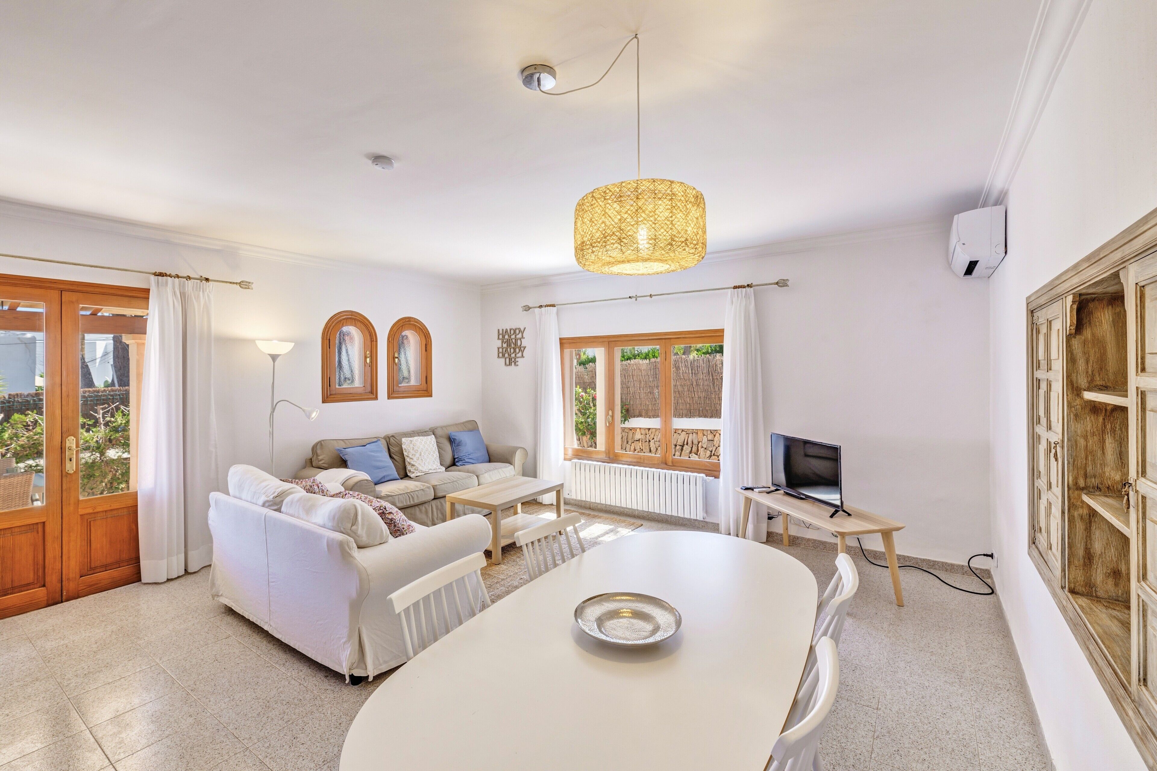 A living room with a sofa, coffee table, TV, and dining table.