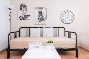 Un lit avec un coffre de rangement intégré, une horloge et deux tableaux encadrés accrochés au mur.