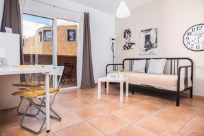 Une pièce comprenant un lit, un bureau, une chaise, une petite table et une fenêtre avec des rideaux.