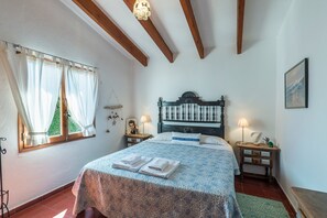 Ein Schlafzimmer mit einem Bett, zwei Nachttischen, einer Lampe, einem Fenster mit Vorhängen und einem gerahmten Bild an der Wand.
