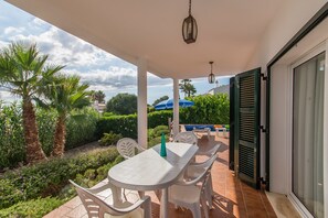 Une terrasse extérieure avec une table et des chaises, entourée de verdure et offrant une vue sur le ciel.