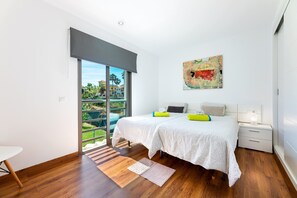 A bedroom with a bed, a nightstand, a window with a view, and a painting on the wall. - Charming Holiday Home Bahamas 2 with Wi-Fi, Pool, Balcony, Terraces & Garden (Son Serra de Marina)