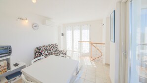 A room with a bed, a desk with a computer, a chair, a sofa, and a balcony with a railing. - In a dreamy location with sea view - Villa Belvedere Nisporto (Rio nell'Elba Livorno)
