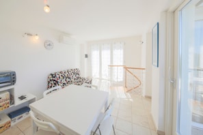 Une chambre comprenant un lit, un bureau avec un ordinateur, une chaise, un canapé et un balcon doté d’une rambarde.