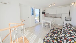 A modern kitchen with white cabinets, a dining table, and a sofa with a colorful pattern. - In a dreamy location with sea view - Villa Belvedere Nisporto (Rio nell'Elba Livorno)