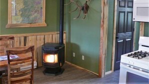 A cozy room with a wood-burning stove, a map on the wall, and a door with antlers.
