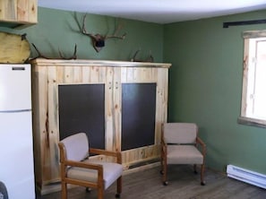 Cozy retreat with a large wardrobe, comfortable armchairs, and a refrigerator.