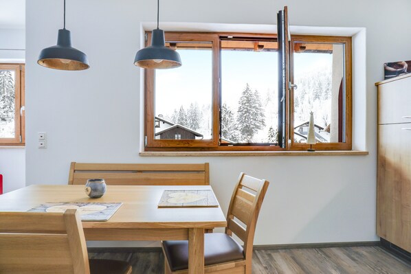 Un coin repas avec une table en bois, deux chaises et des lampes suspendues.