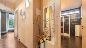 A wooden interior with a mirror, a vase with flowers, and a view of a bathroom with a shower and toilet. - Idyllic and with spectacular mountain views – Apartment GeoResort C10 (Tremosine)