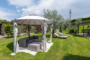 Un espace patio doté d’un coin salon abrité, de mobilier d’extérieur et d’une vue sur le jardin environnant.