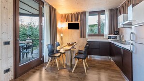 A modern kitchen with a dining area, wooden flooring, and large windows. - Idyllic and with spectacular mountain views – Apartment GeoResort C10 (Tremosine)
