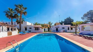Ein Swimmingpool mit Liegestühlen, Palmen und weißen Gebäuden.