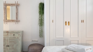 Une chambre à coucher avec un lit, une armoire, un miroir et une plante suspendue.