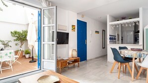 Un salon moderne avec un coin repas, une porte bleue et une cuisine équipée d’un four encastré.