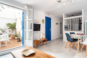 A modern living room with a dining area, a blue door, and a kitchen area with a built-in oven.