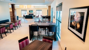 Rebedor d'hotel modern amb diverses zones d'estar, un bar i grans finestres que aporten llum natural.