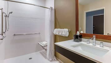 A modern bathroom with a walk-in shower, a large mirror, and a dual sink vanity.