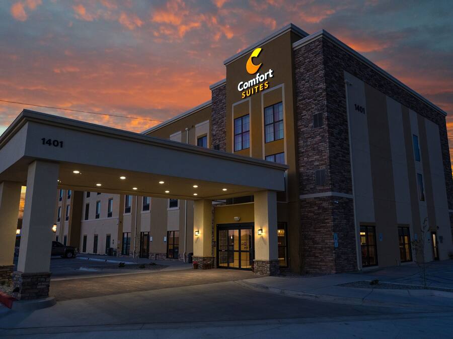 Modernilla designilla varustettu Comfort Suites -hotelli, jossa on näyttävä sisäänkäynti ja taustalla avoin, selkeä taivas.