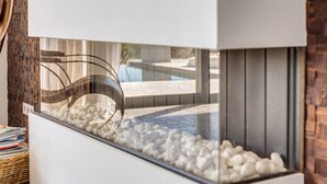 A modern fish tank with white pebbles and a clear glass front, located in a room with a brick wall and a window. - Air-Conditioned Villa with Sea View, Pool, Jacuzzi, Rooftop Gym/Terrace & Wi-Fi (Costa De La Calma, CALVIÀ)