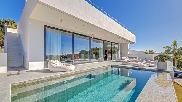 A modern house with a swimming pool, large glass windows, and outdoor seating. - Air-Conditioned Villa with Sea View, Pool, Jacuzzi, Rooftop Gym/Terrace & Wi-Fi (Costa De La Calma, CALVIÀ)