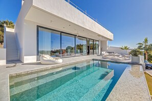 A modern house with a swimming pool, large glass windows, and outdoor seating. - Air-Conditioned Villa with Sea View, Pool, Jacuzzi, Rooftop Gym/Terrace & Wi-Fi (Costa De La Calma, CALVIÀ)