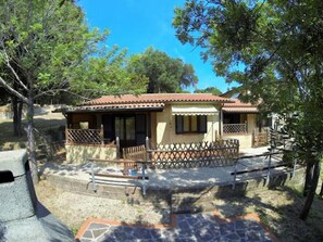 A two-story building with a tiled roof, a covered patio, and a fenced garden area.