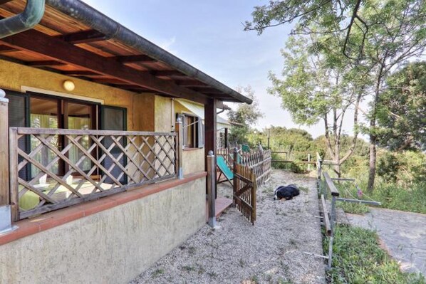 Un bâtiment doté d’un balcon en bois, d’un espace extérieur clôturé et d’un chemin pavé.