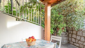 Una mesa con mantel estampado, una cesta de mimbre con frutas y una silla blanca.