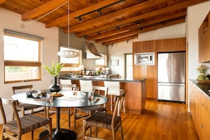 Una cocina moderna con armarios de madera, un refrigerador de acero inoxidable y un comedor con una mesa redonda y sillas.