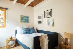 Un dormitorio con cama, una mesita de noche con lámpara y una obra de arte en la pared.