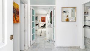 A hallway with open doors leading to a dining area, a kitchen, and a bathroom.