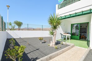 A building with a green door, a small patio with plants, and a clear view of the mountains in the background.