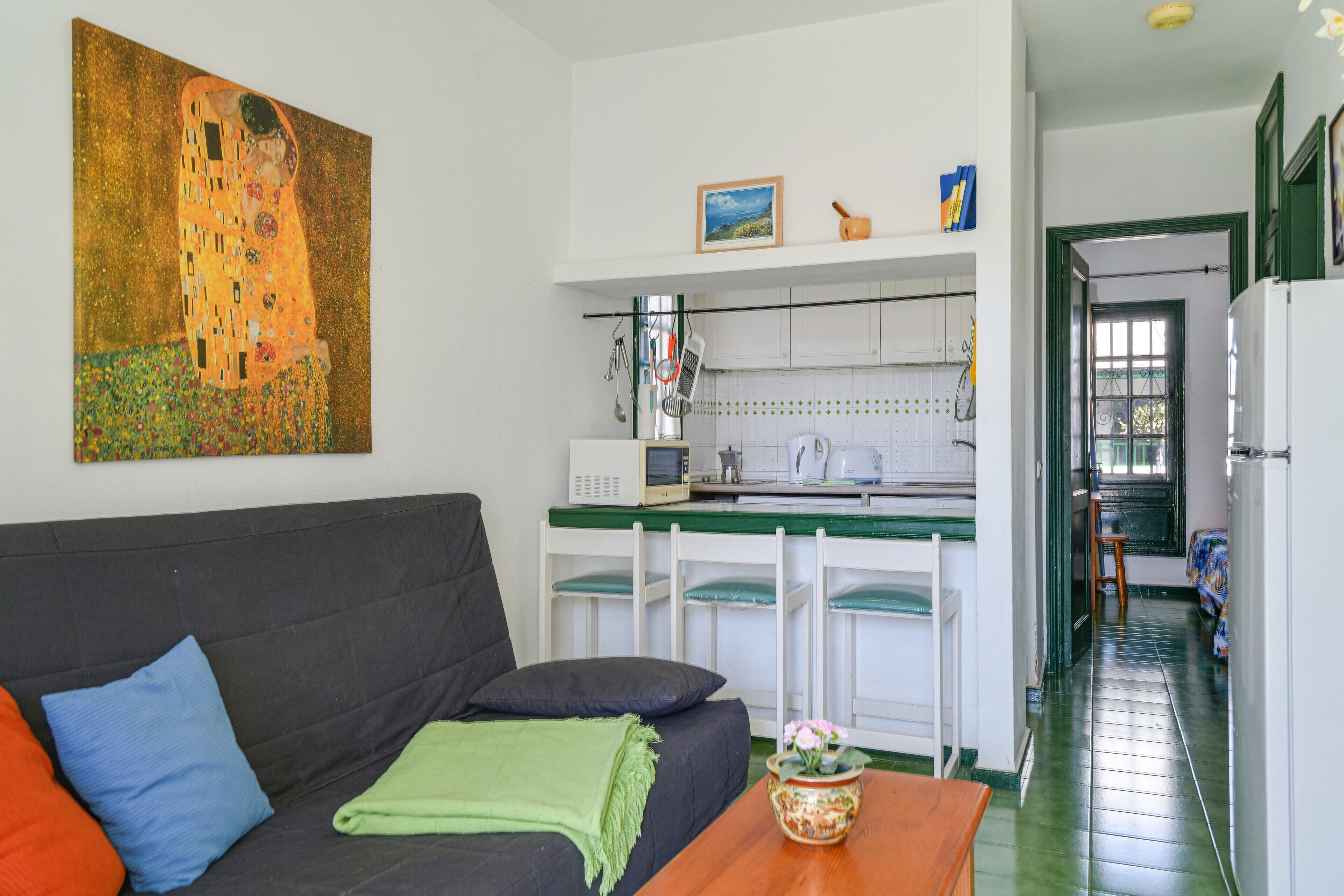 Een woonkamer met een bank, een tafel en een schilderij aan de muur.