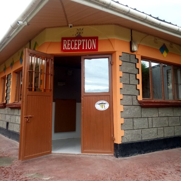A reception area with a sign, a wooden door, and a window. - Petluck Resort Naivasha (Naivasha)
