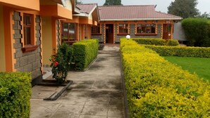 Un edificio con un sendero que conduce a la entrada, rodeado de setos cuidados y un pequeño jardín.