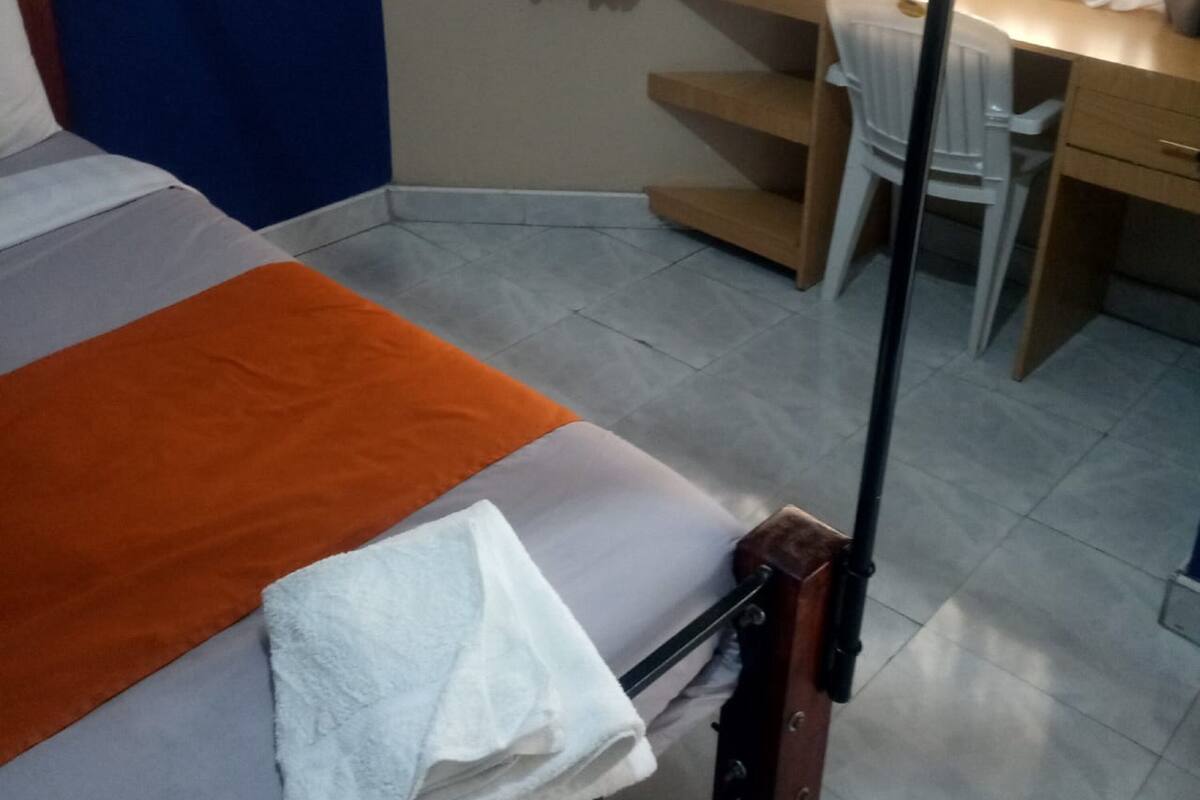 A bedroom with a bed, a desk, and a chair.