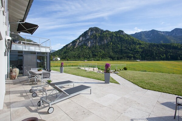 Une terrasse aménagée avec du mobilier d’extérieur, une table et des chaises, offrant une vue sur un paysage montagneux.