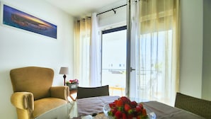 Een kamer met een bed, een stoel, een tafel met een fruitschaal, een lamp en een raam met gordijnen.