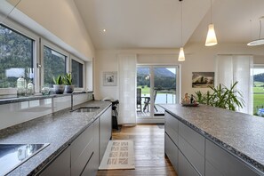 Una cocina moderna con encimeras de granito, vistas a un lago y un comedor con mobiliario de exterior.