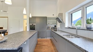 Una cucina moderna con ripiani in granito, forno integrato e un'ampia finestra con vista sulle montagne.