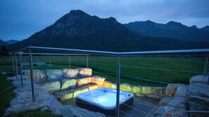 Una vasca idromassaggio immersa in un paesaggio naturale con montagne sullo sfondo.