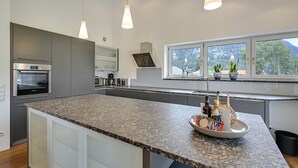 Una cucina moderna con piani in granito, elettrodomestici in acciaio inossidabile e un'ampia finestra vista alberi.