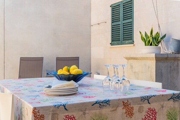 A table with a floral tablecloth, a bowl of lemons, and clear glassware.