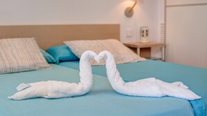 Un lit avec une couvre-lit bleue, deux oreillers et une lampe fixée au mur.
