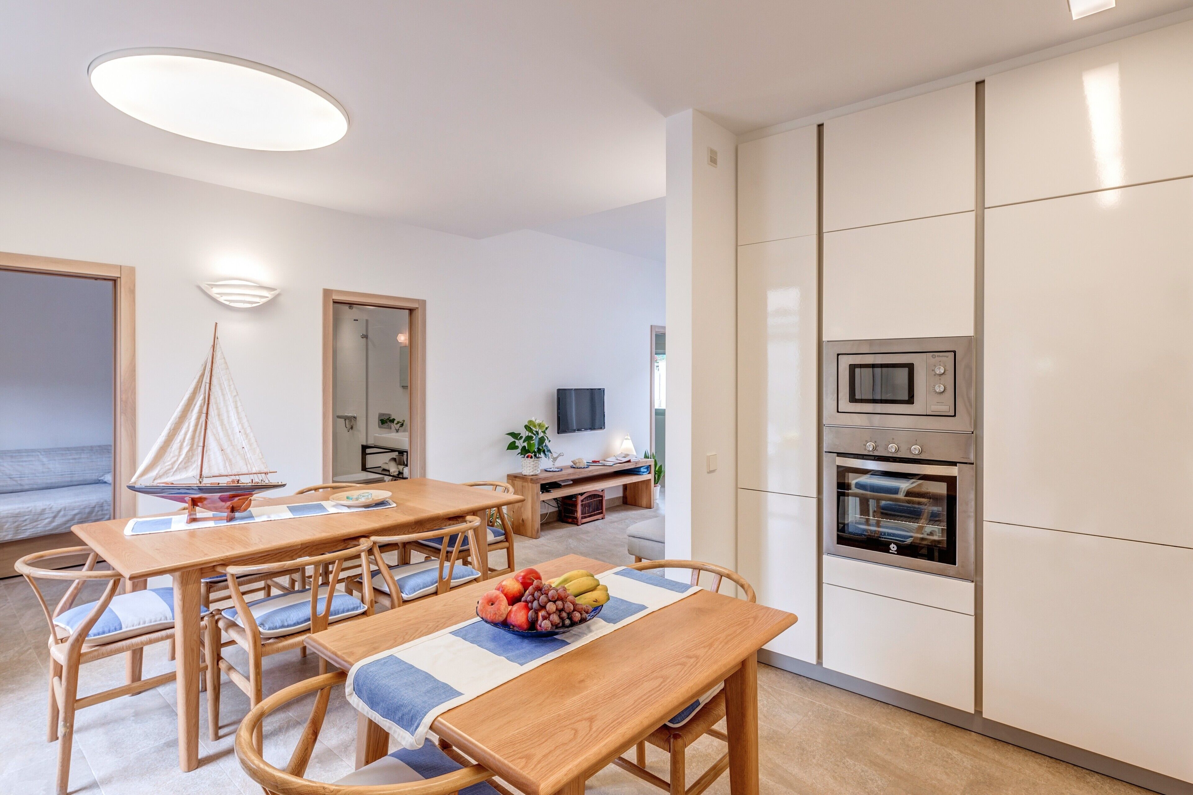 Una cocina moderna con electrodomésticos integrados, un comedor con mobiliario de madera y una decoración con motivos náuticos.