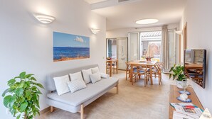 Un salon moderne comprenant un canapé, une table à manger, des chaises et un téléviseur.