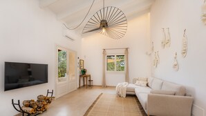Uma sala de estar moderna com televisão de tela plana, sofá, mesa de centro, luminária decorativa e janela com cortinas.