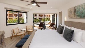 A hotel room with a large bed, a ceiling fan, a view of the outdoor pool area, and a painting on the wall.